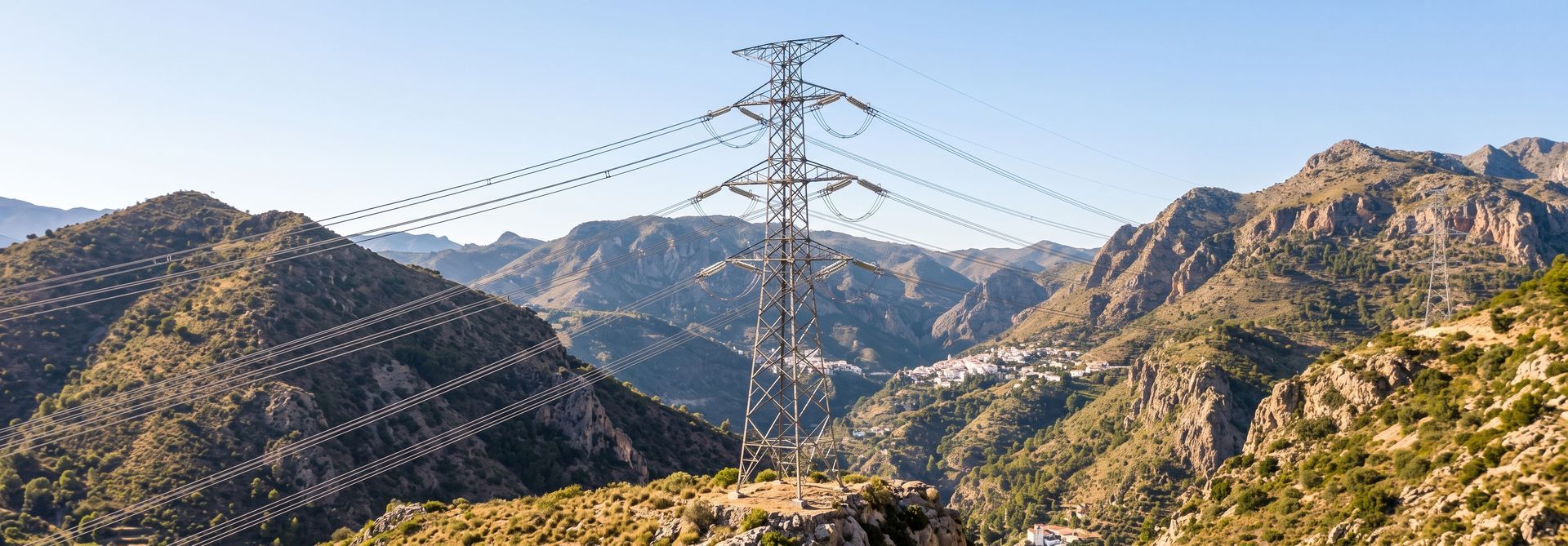 Mountain valley with power transmission towers and lines under a clear sky
