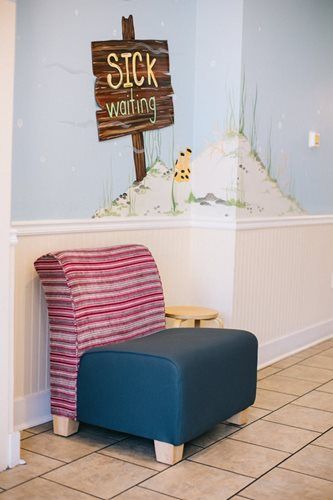 Chair with blue seat and striped back near a wall mural and a small stool.