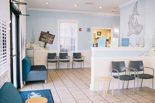 Waiting room with blue walls and chairs, decorated with a shark mural and an 