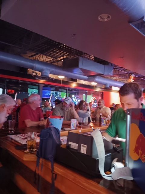 A group of people sitting at a bar with a red bull sign