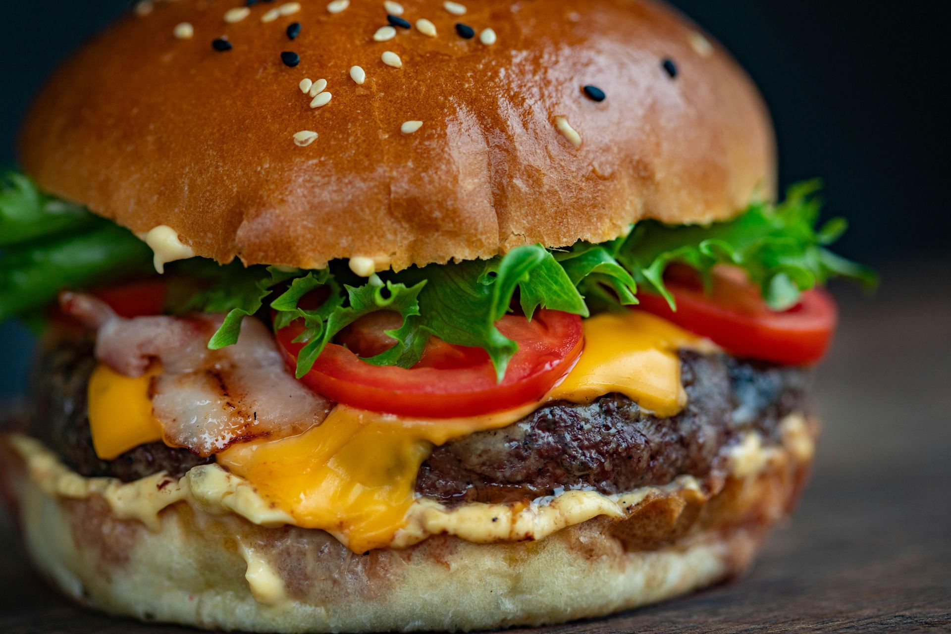 Cheeseburger with bacon, tomato, lettuce, and sesame seed bun.