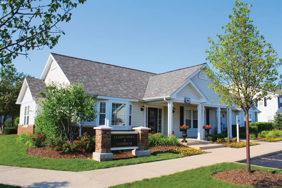 a white house with a gray roof and a sign in front of it