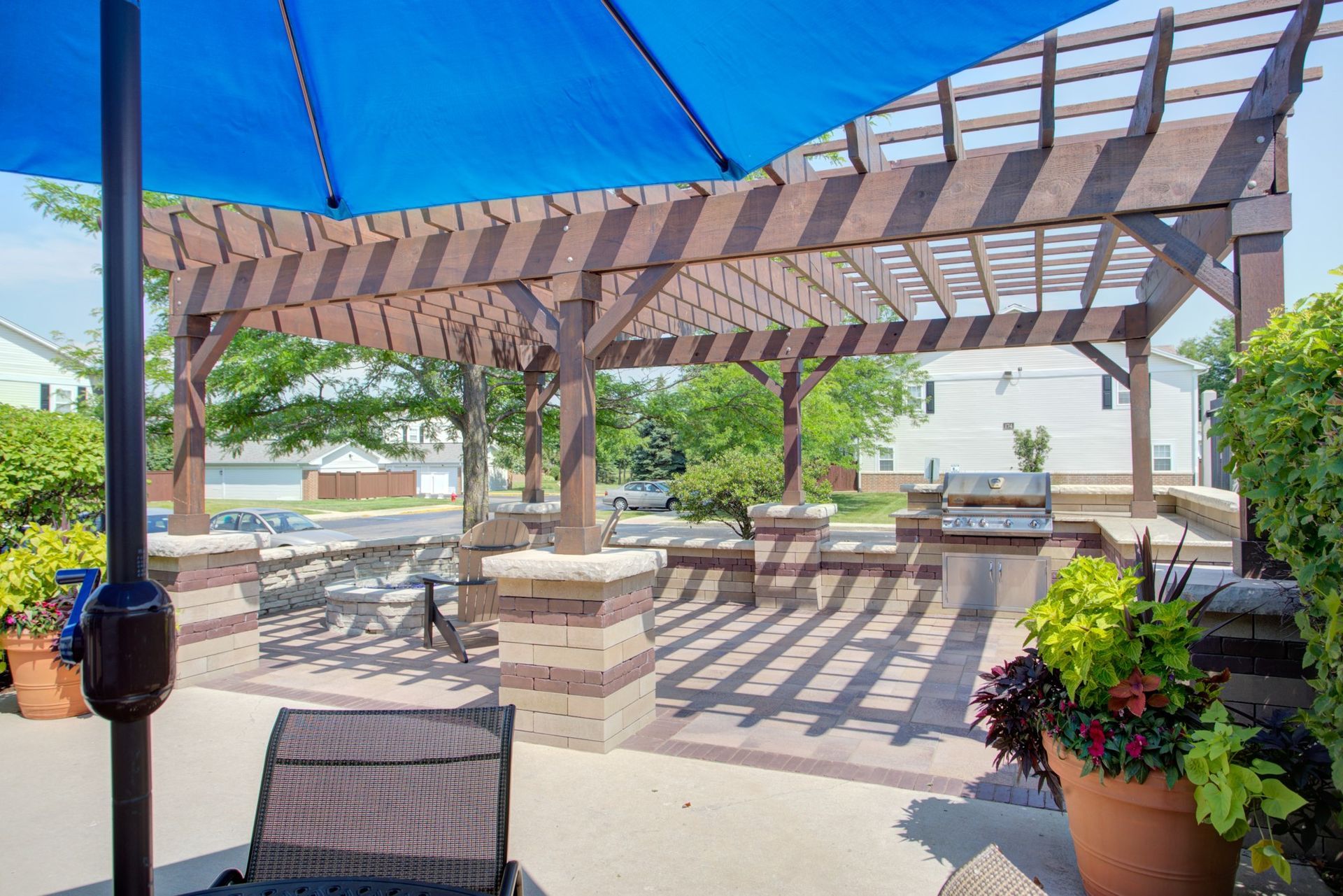 a blue umbrella is sitting under a pergola on a patio .