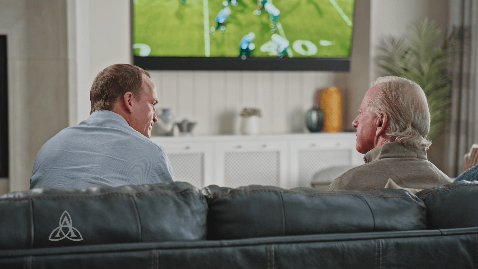 Peyton & Archie Manning sitting on a couch in a health care TV commercial
