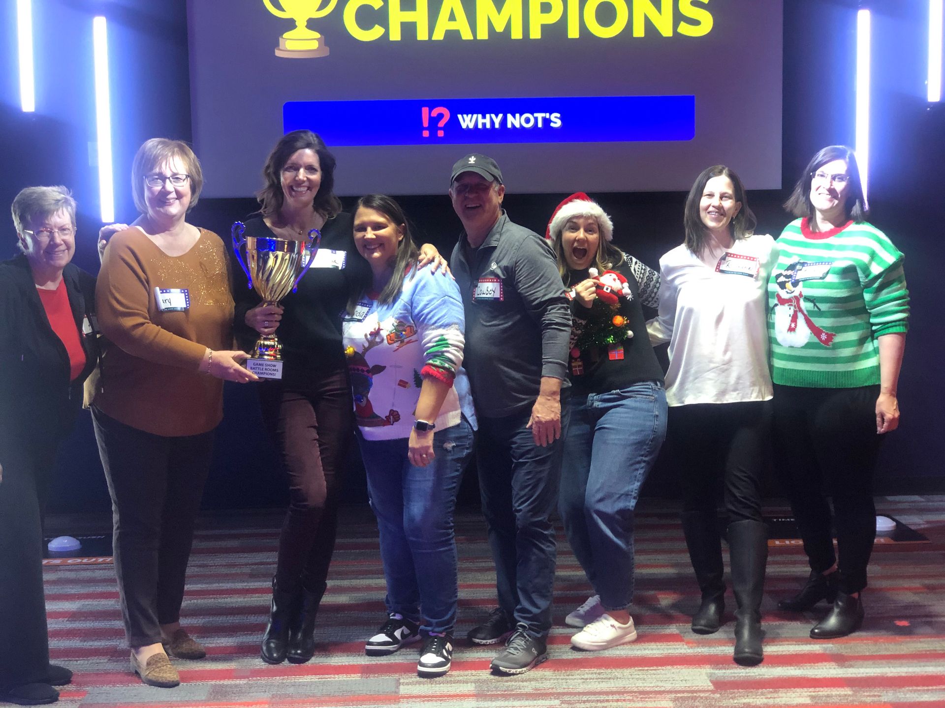 A group of people are posing for a picture in front of a screen that says champions.