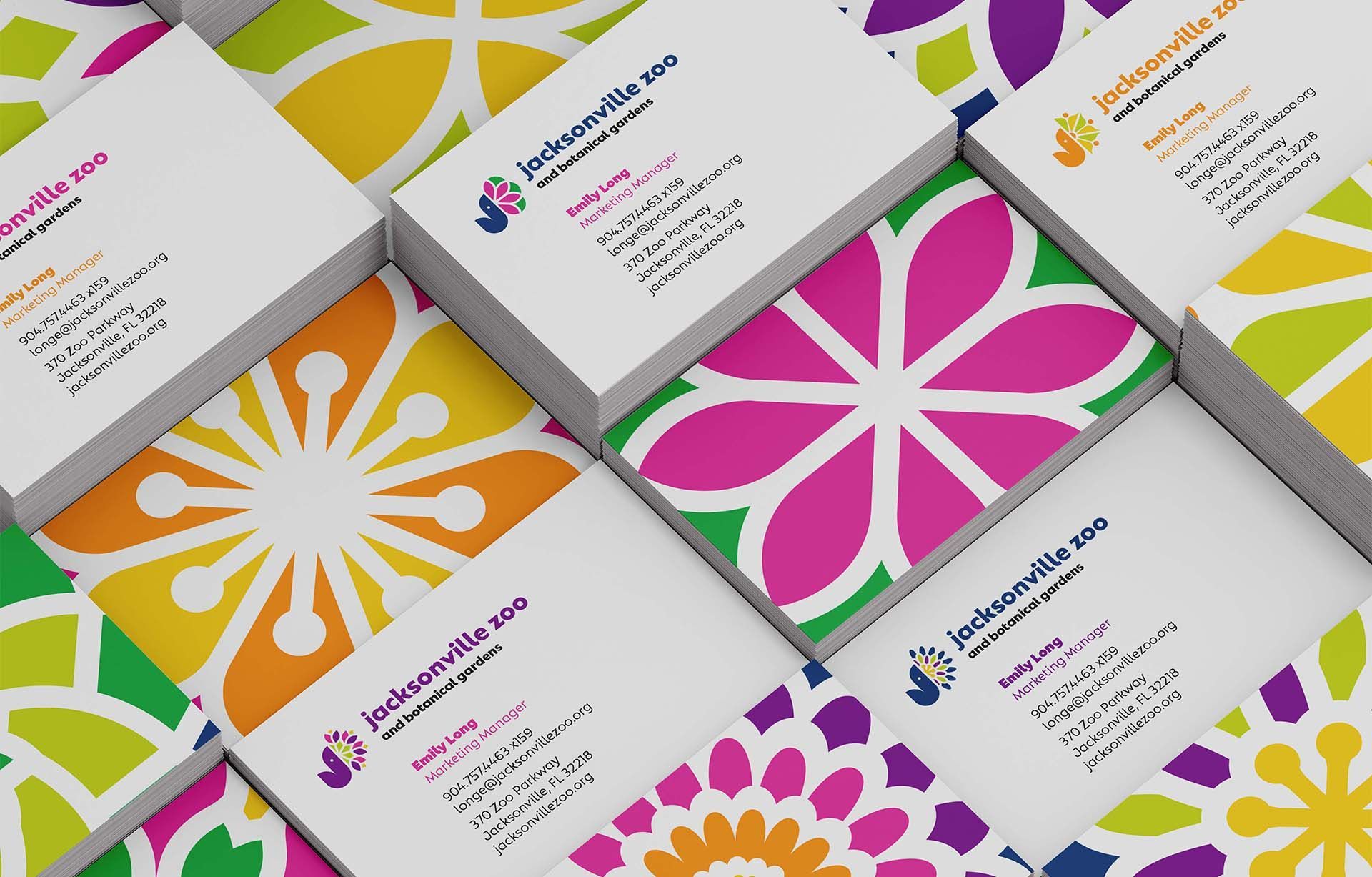 Colorful business cards with bold floral patterns in pink, orange, yellow, and purple on a white surface