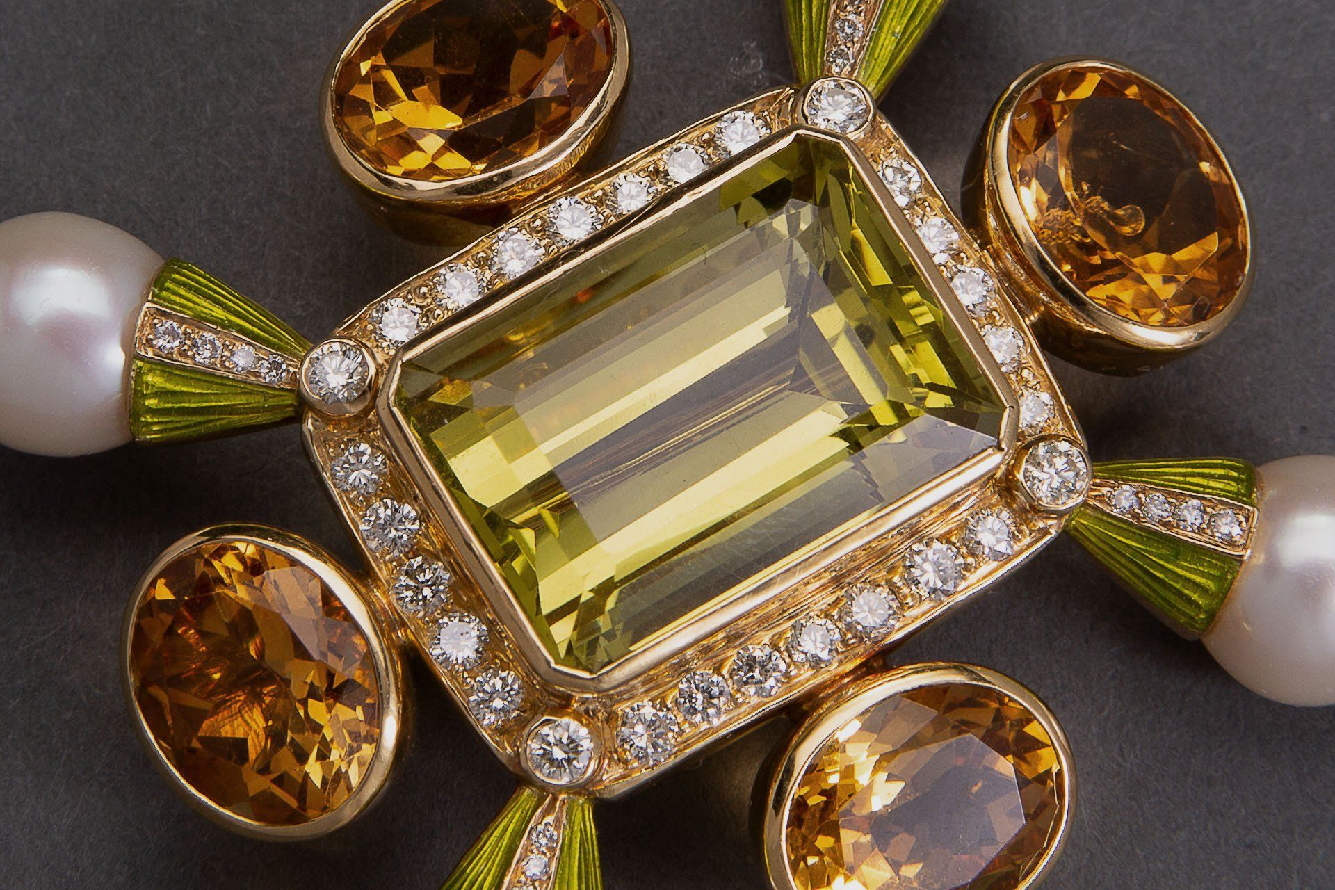 Gold and amber gemstone brooch with a rectangular center stone and pearl accents on a dark background