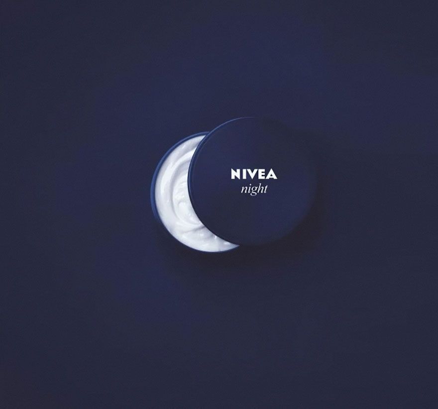 A jar of nivea night cream is sitting on a dark blue surface.