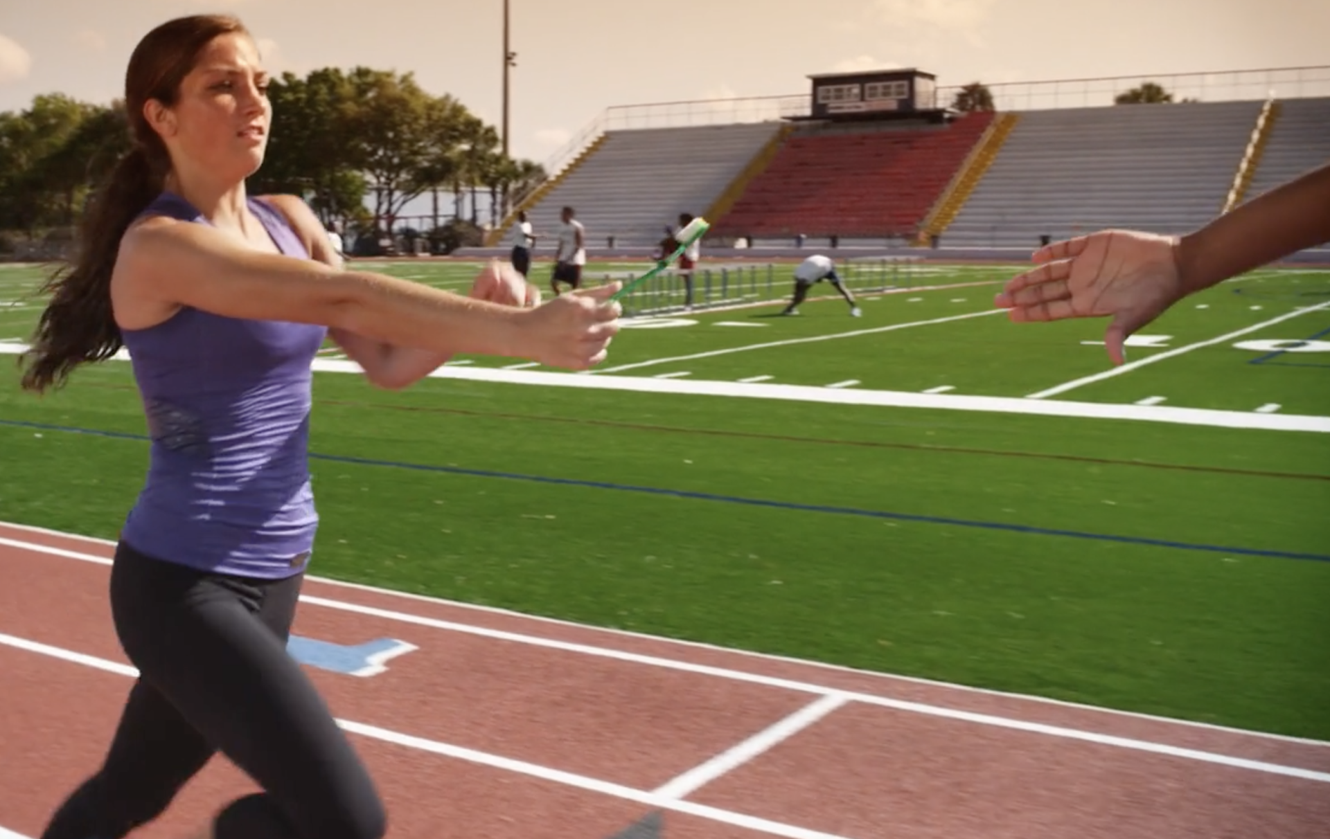 A woman in a purple tank top is running on a track