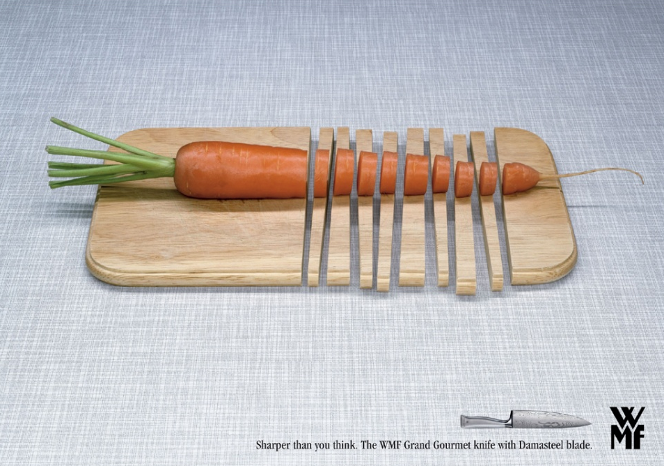 A carrot on a wooden cutting board with knives on it