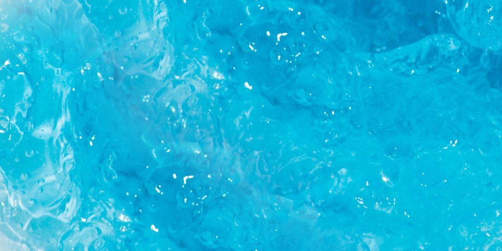 A close up of a blue water surface with bubbles coming out of it.