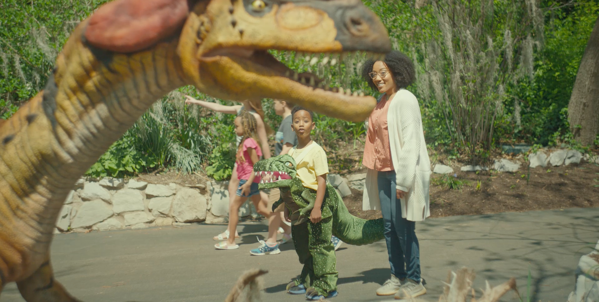 A group of people are standing in front of a dinosaur statue.