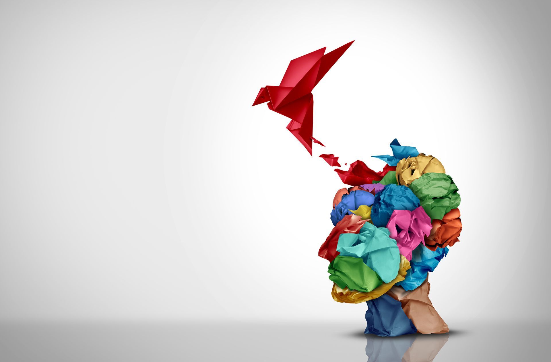 A colorful origami bird is flying out of a person 's head