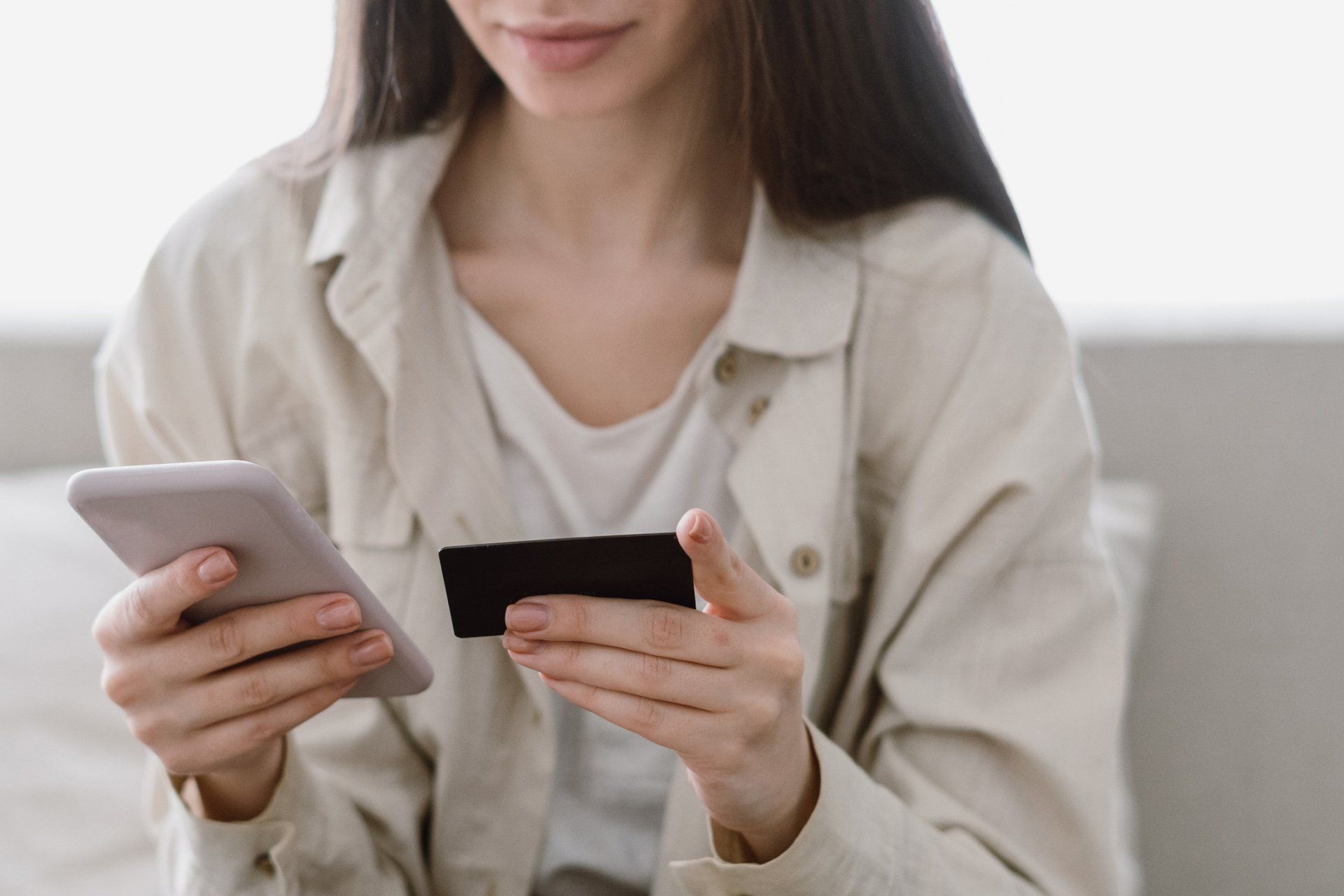 A woman is holding a credit card and a cell phone.