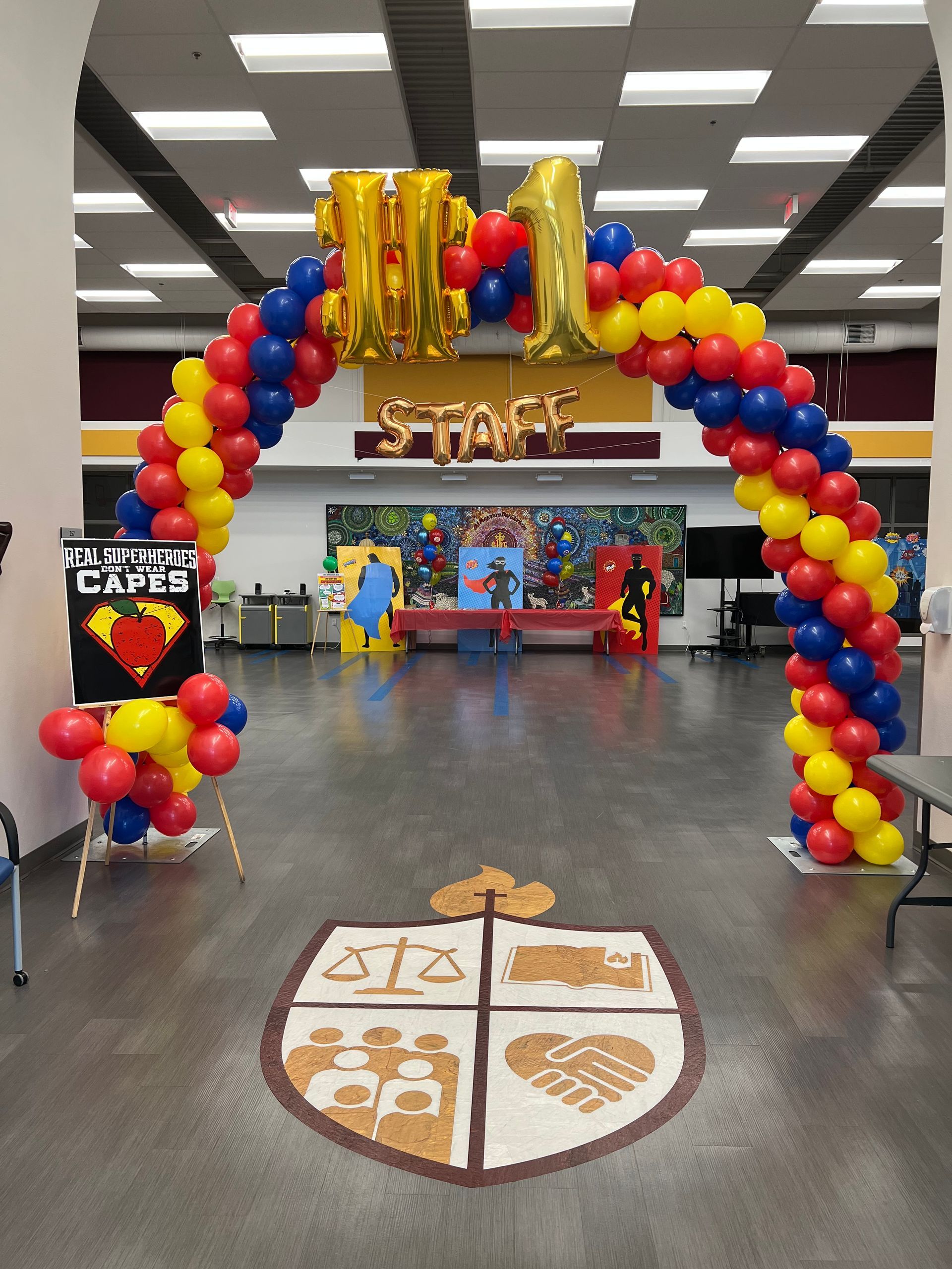 A balloon arch in a room with a shield on the floor