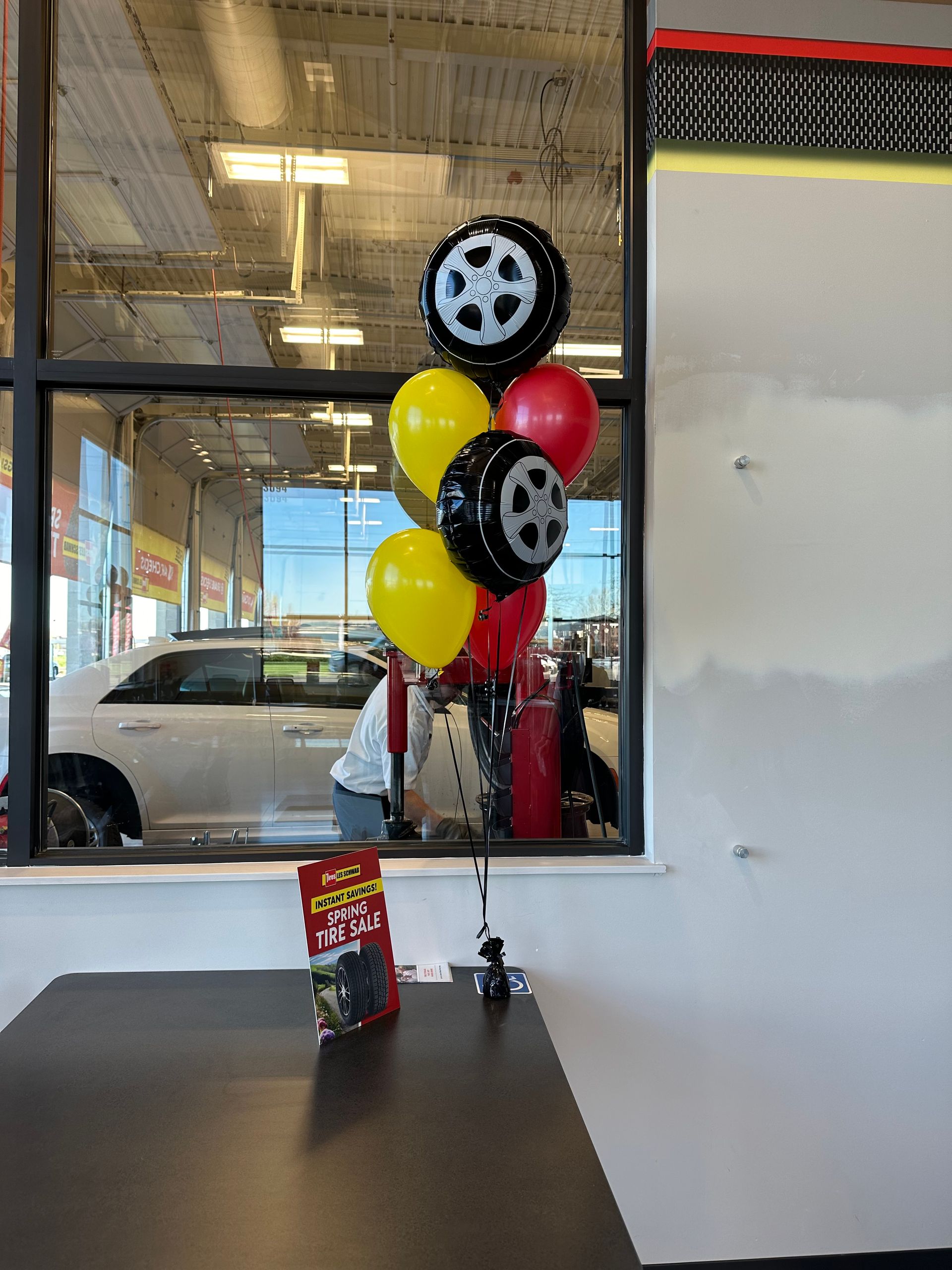 A bunch of balloons in the shape of tires are sitting on a table in a car dealership.