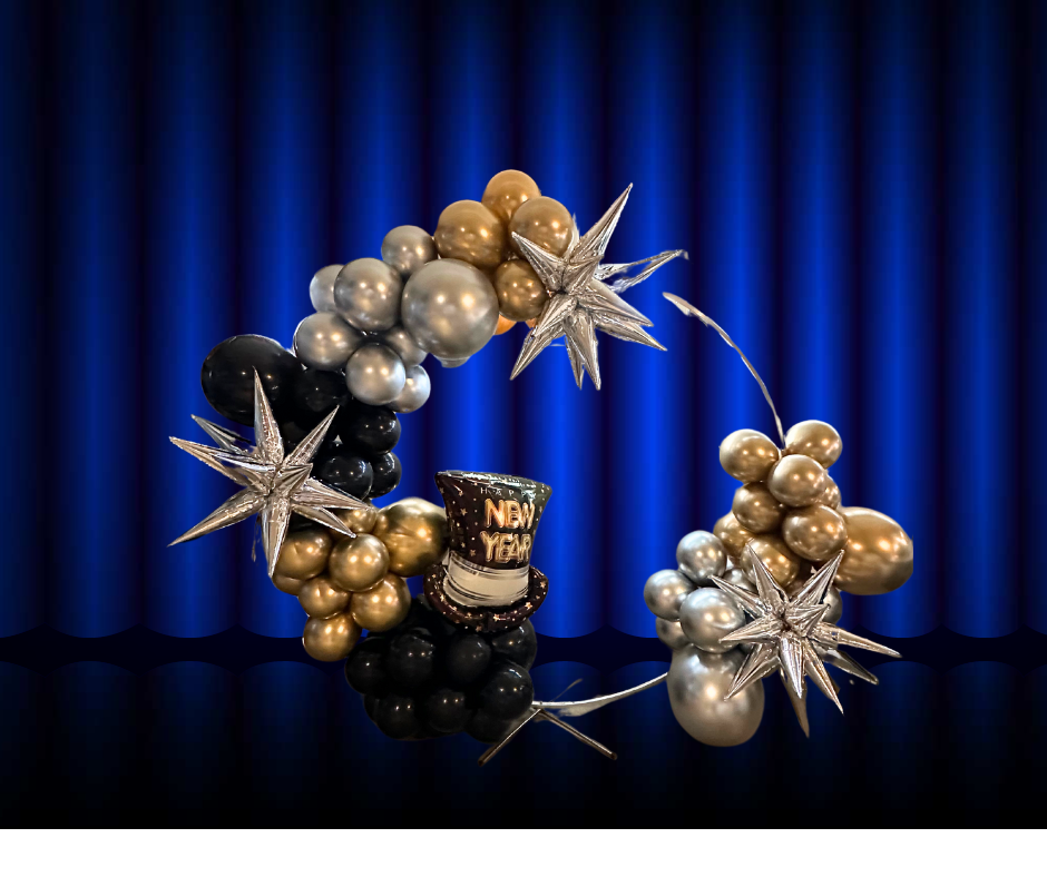 A wreath of balloons with a top hat and stars on a blue curtain.