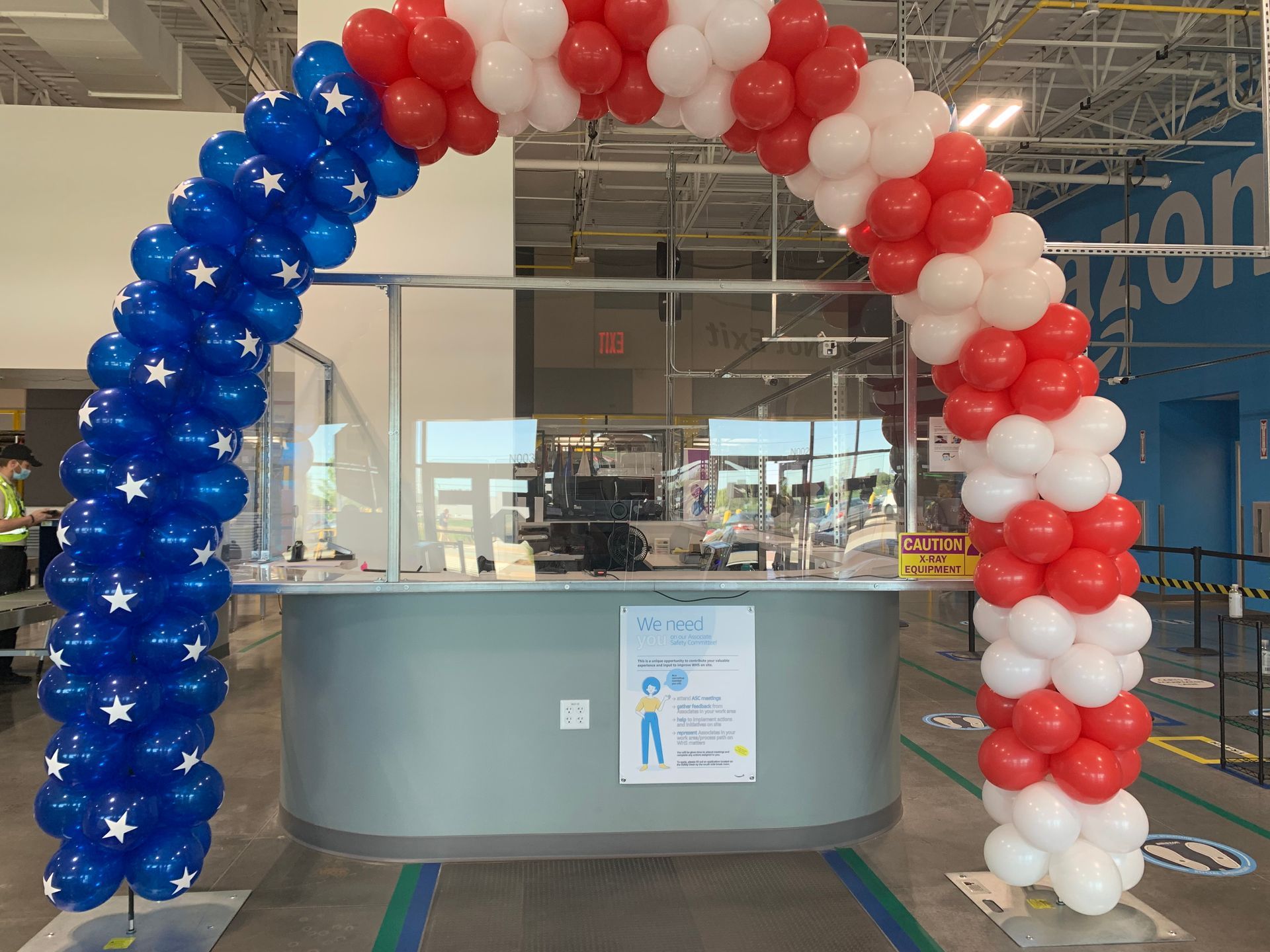 A red , white and blue balloon arch in front of a counter.