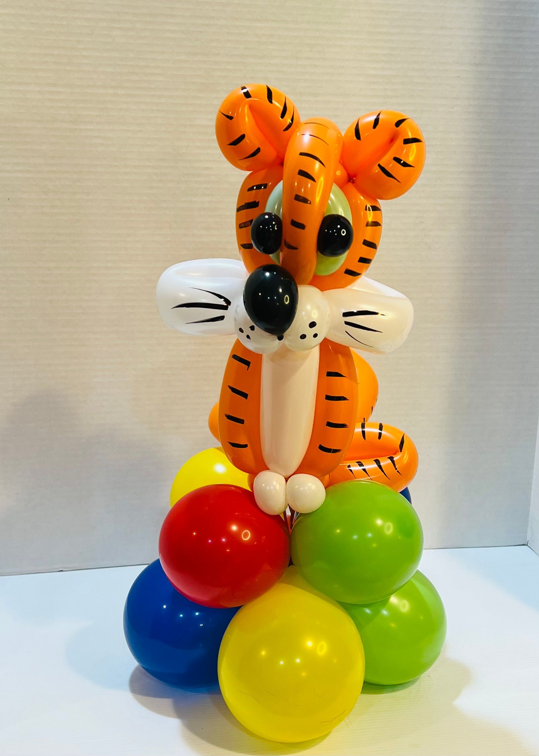 A tiger made out of balloons is sitting on a pile of balloons