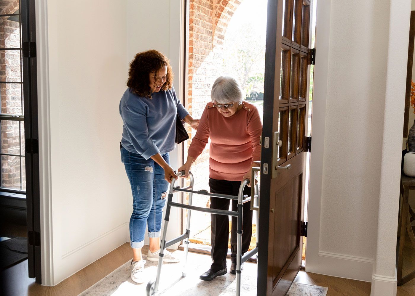A woman is helping an elderly woman with a walker.