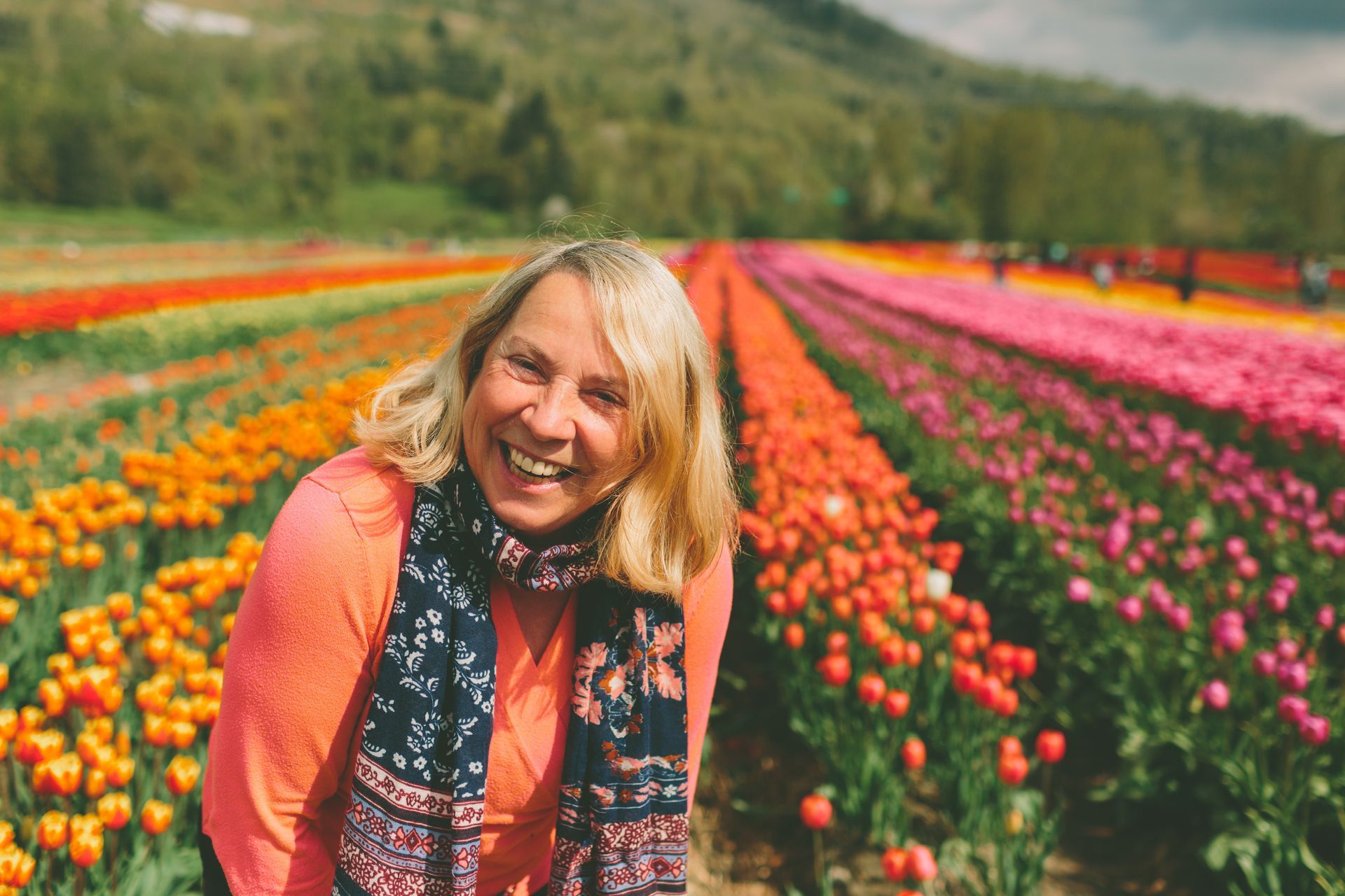 A woman is smiling in a field of flowers.