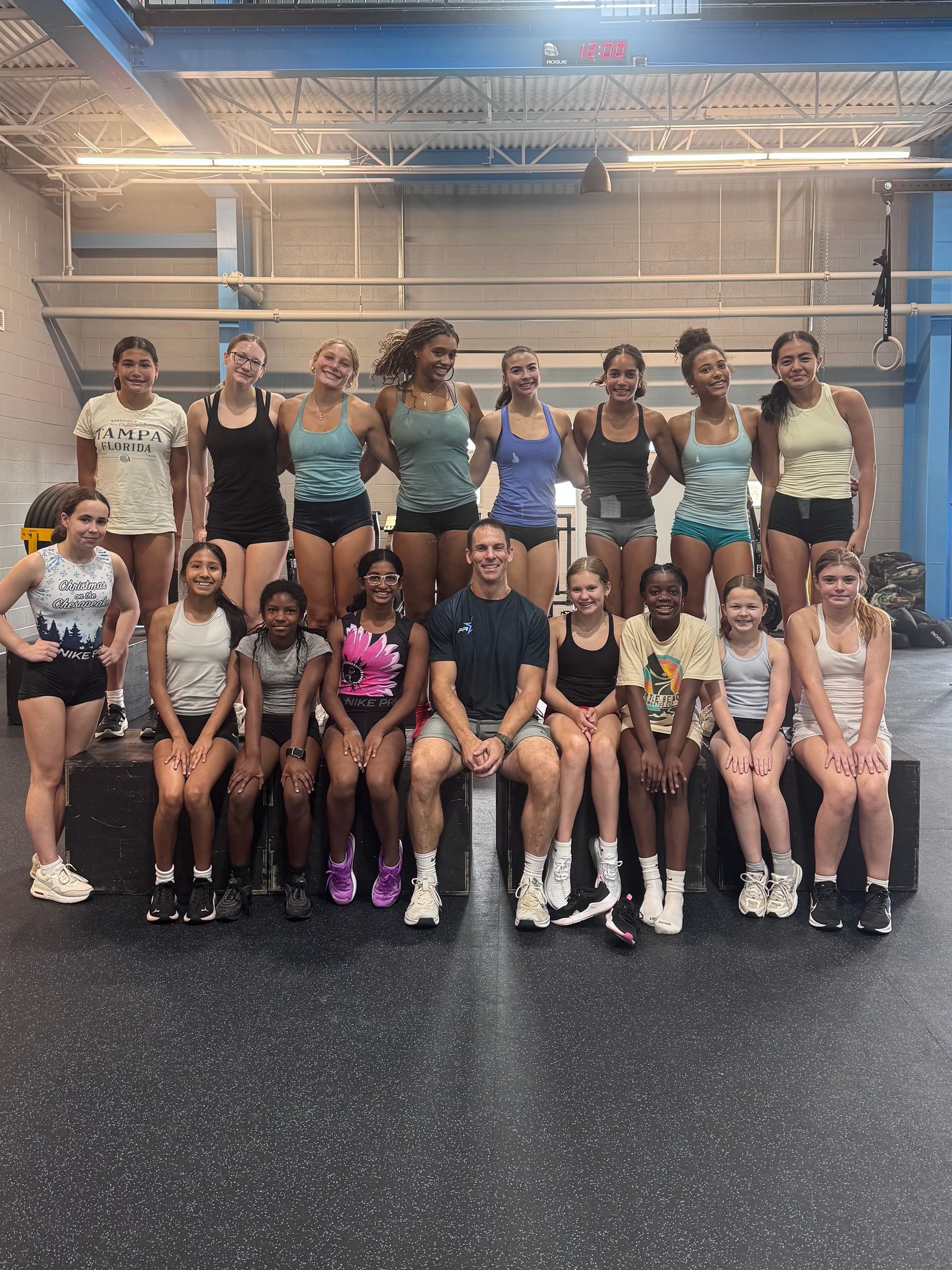 Group of athletes posing in a gym, wearing matching teal and black uniforms.