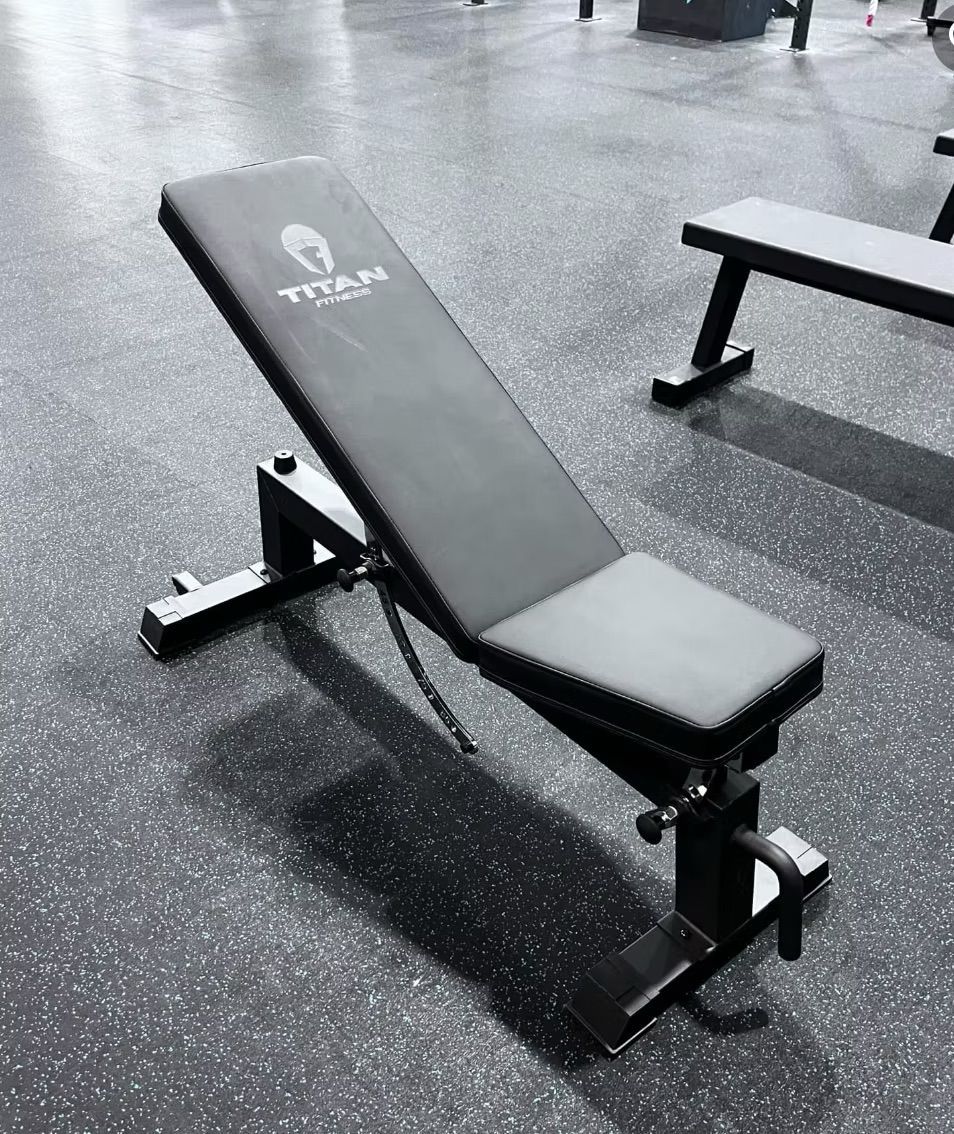 Incline weight bench in a gym with black flooring and another bench in the background
