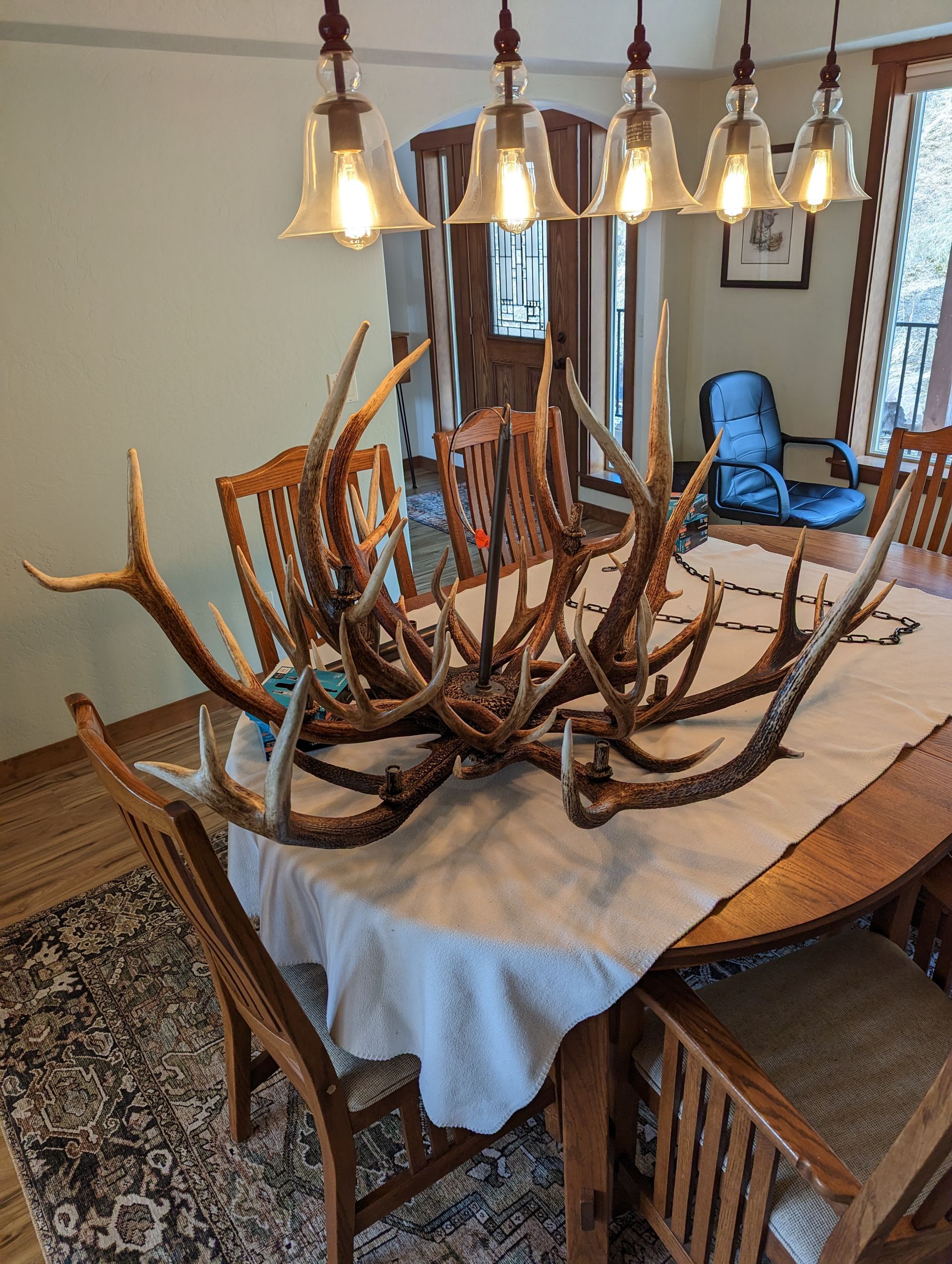 A dining room table with antlers on it and a chandelier hanging from the ceiling.