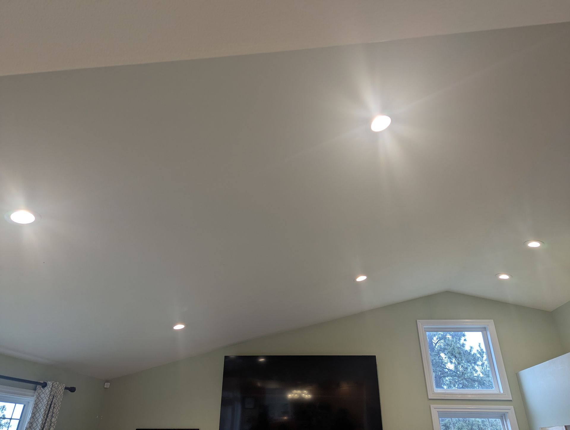 A living room with a vaulted ceiling and a flat screen tv.