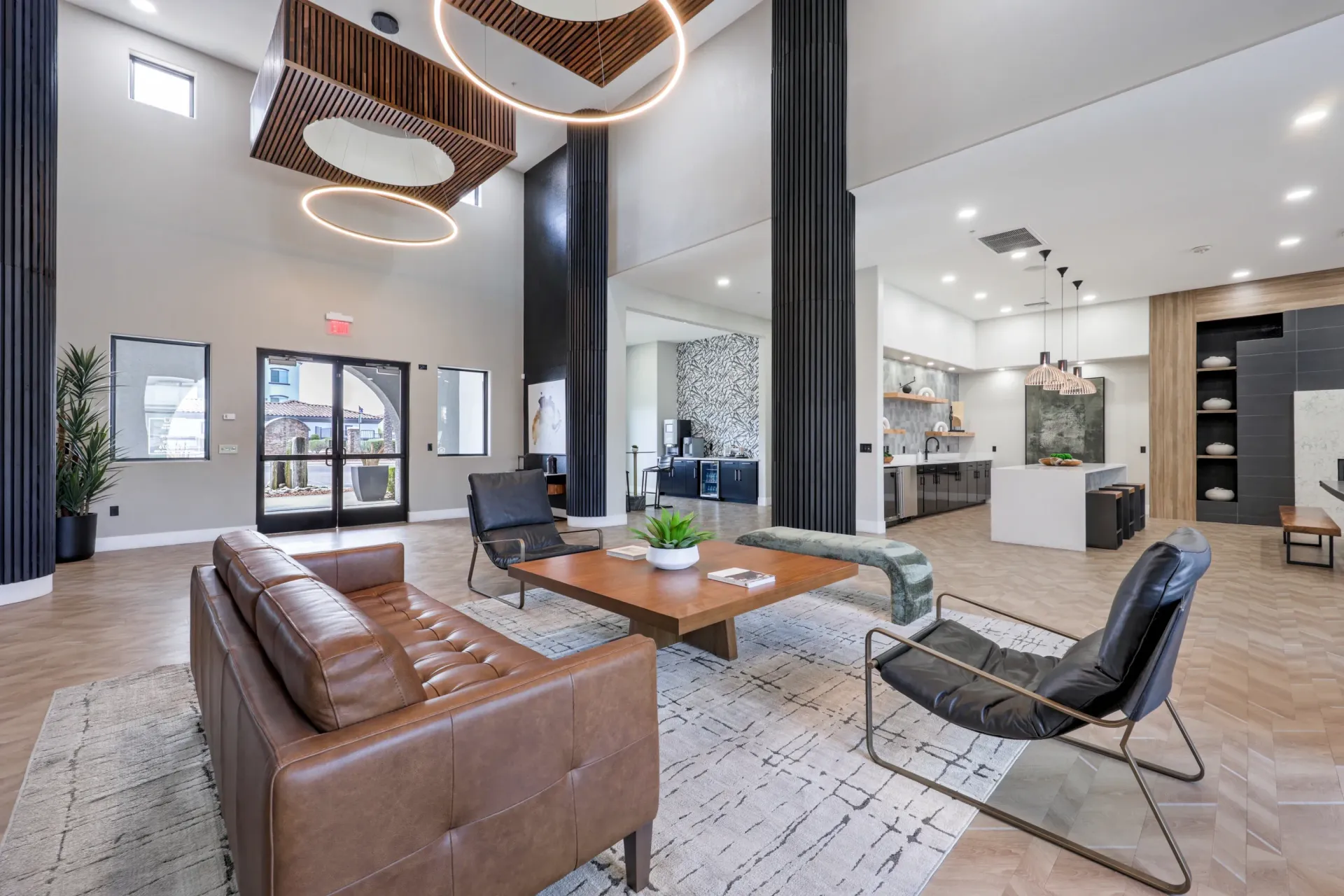 Modern apartment building lobby with comfortable seating, a coffee bar, and a sleek kitchen area.