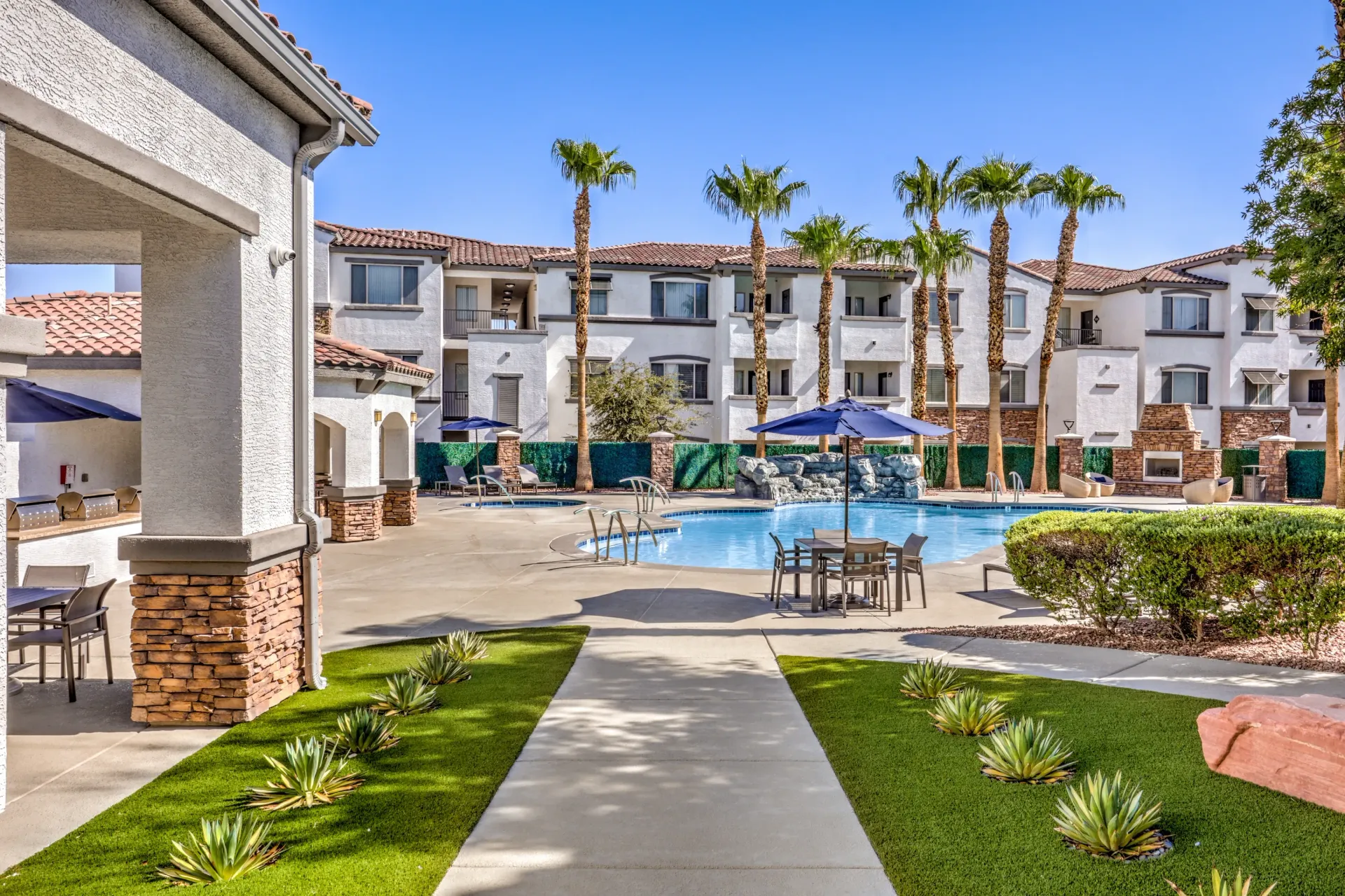 Resort-style swimming pool with water feature and lounge chairs in a multifamily community at Cornerstone Park in Henderson, NV.