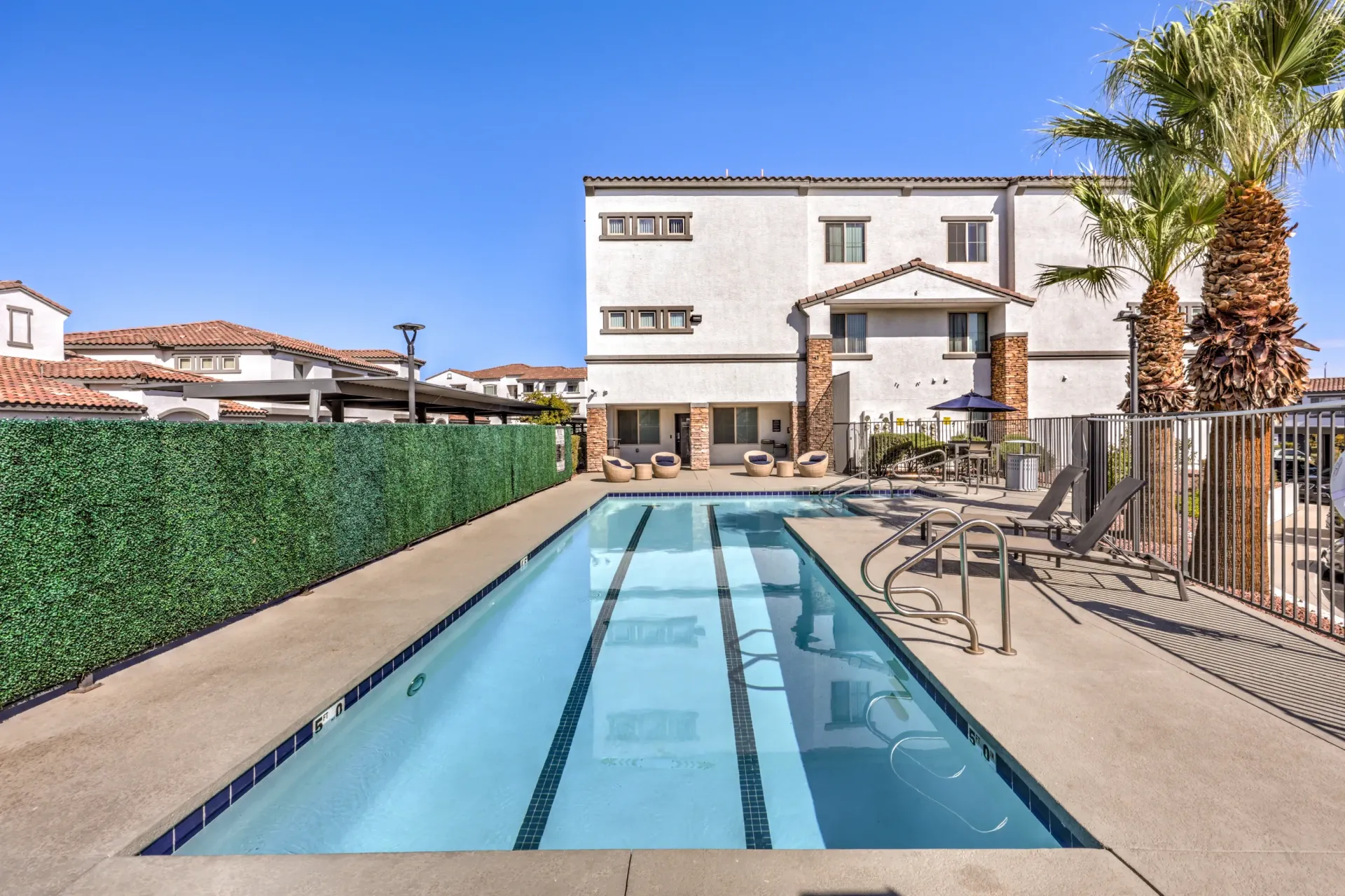Swimming pool with lounge chairs and palm trees at a multifamily property at Cornerstone Park in Henderson, NV.