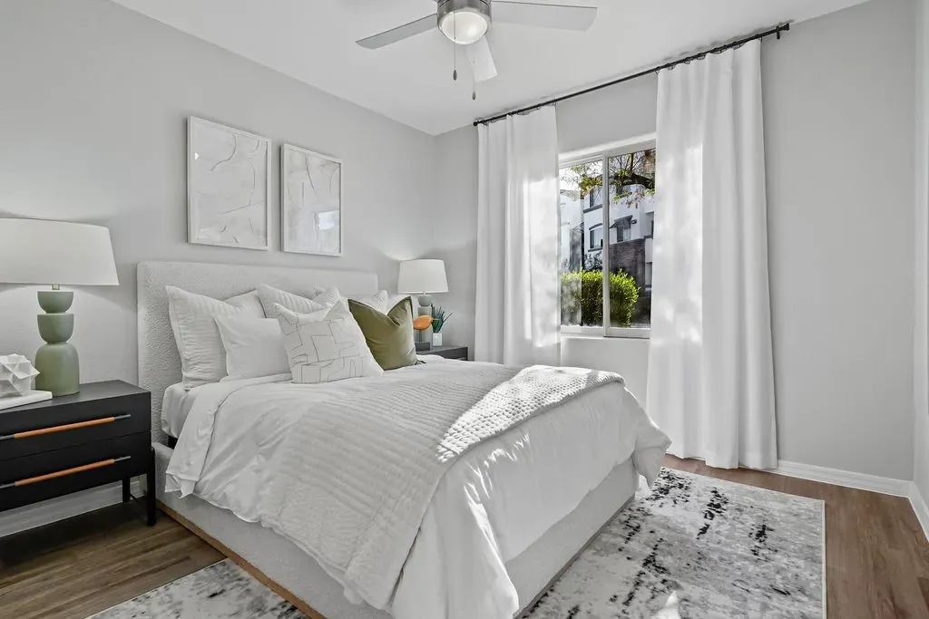 Modern bedroom with a king-size bed, white linens, and a green accent pillow at Cornerstone Park in Henderson, NV.