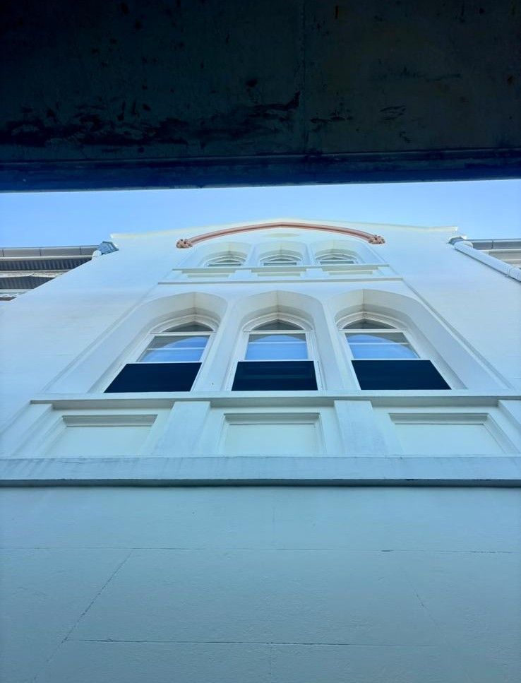 Restored arched timber windows on a white heritage building facade