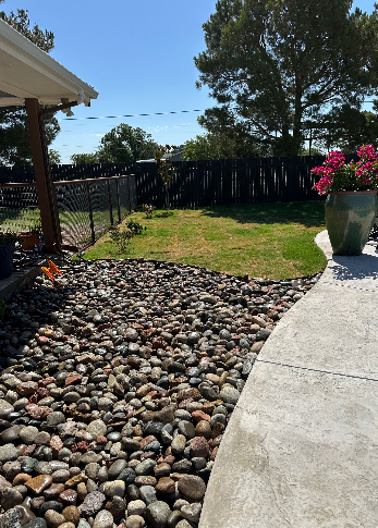 A one-story light gray house with a long porch, a brick walkway, and landscaping.