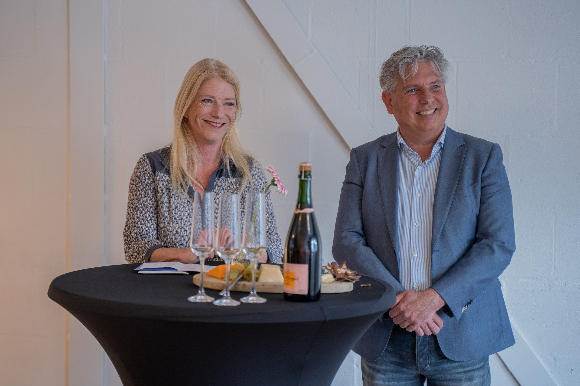 Een man en een vrouw zitten aan een tafel met een fles wijn.