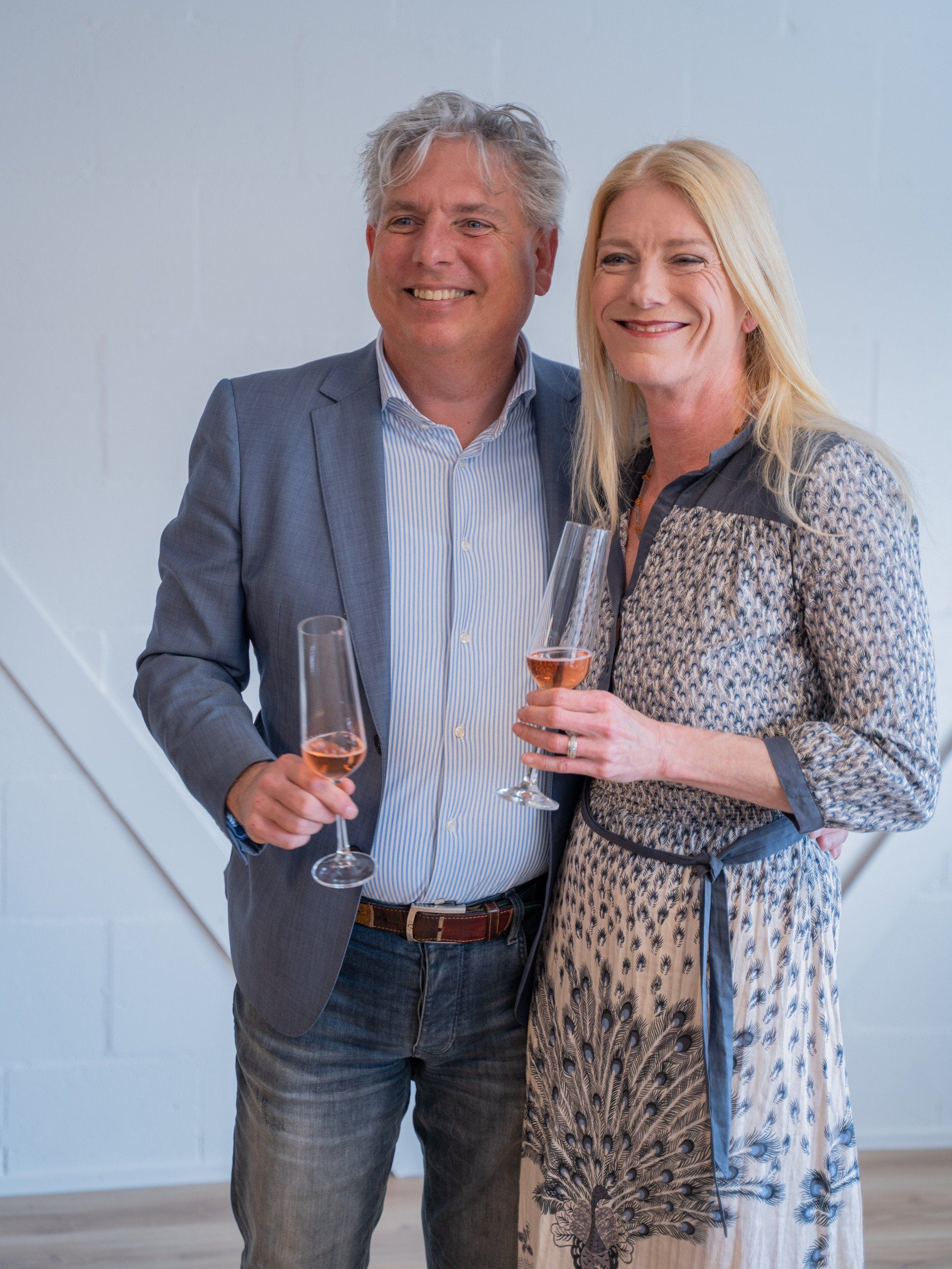 Een man en een vrouw staan naast elkaar met wijnglazen in hun handen.