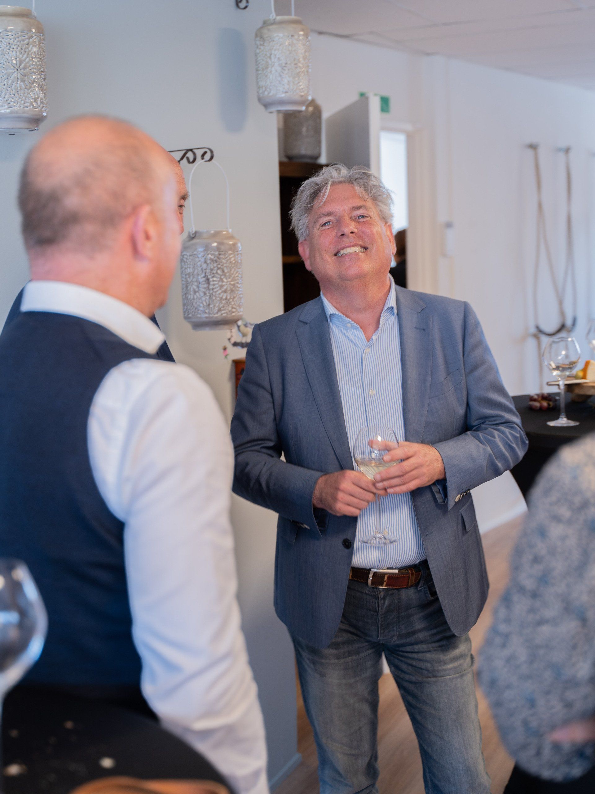 Een man in een pak lacht terwijl hij een glas wijn vasthoudt