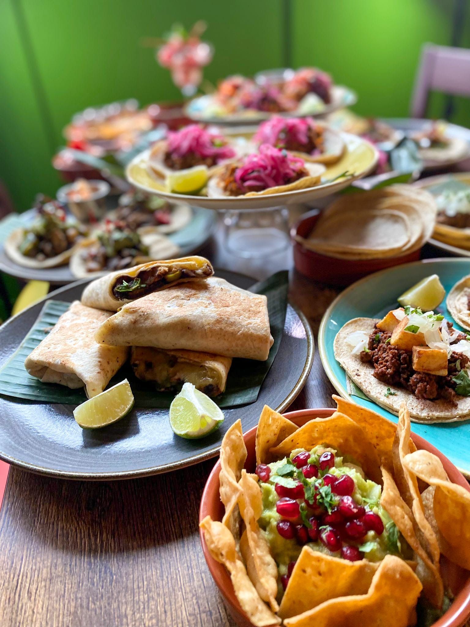 A table topped with plates of food and a bowl of guacamole