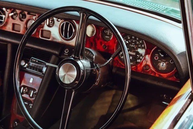 The interior of an old car with a steering wheel and dashboard.
