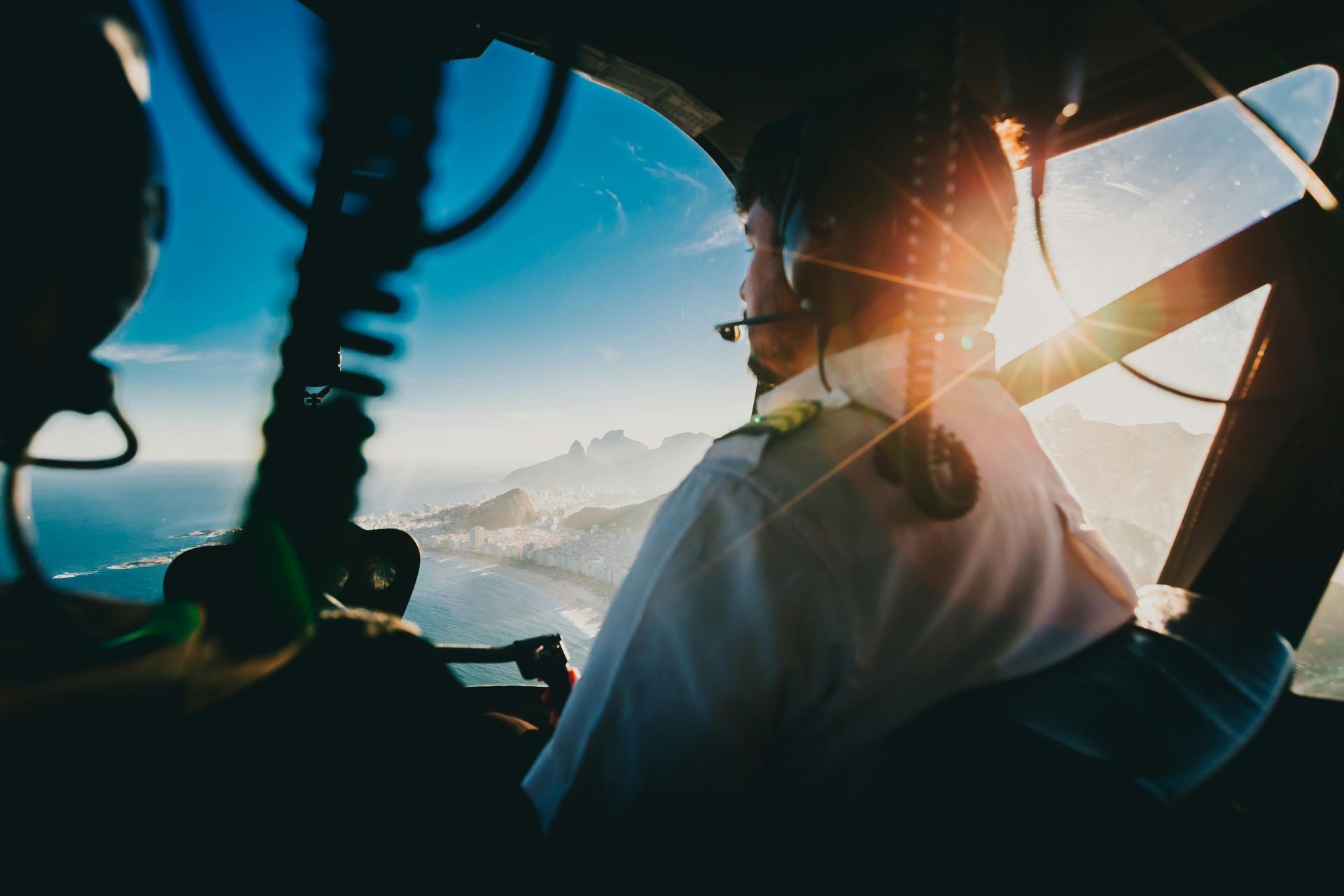 A pilot is sitting in the cockpit of a helicopter looking out the window.