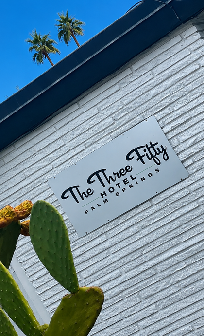 White brick storefront with a sign reading “The Three …” and a lit lantern by the entrance