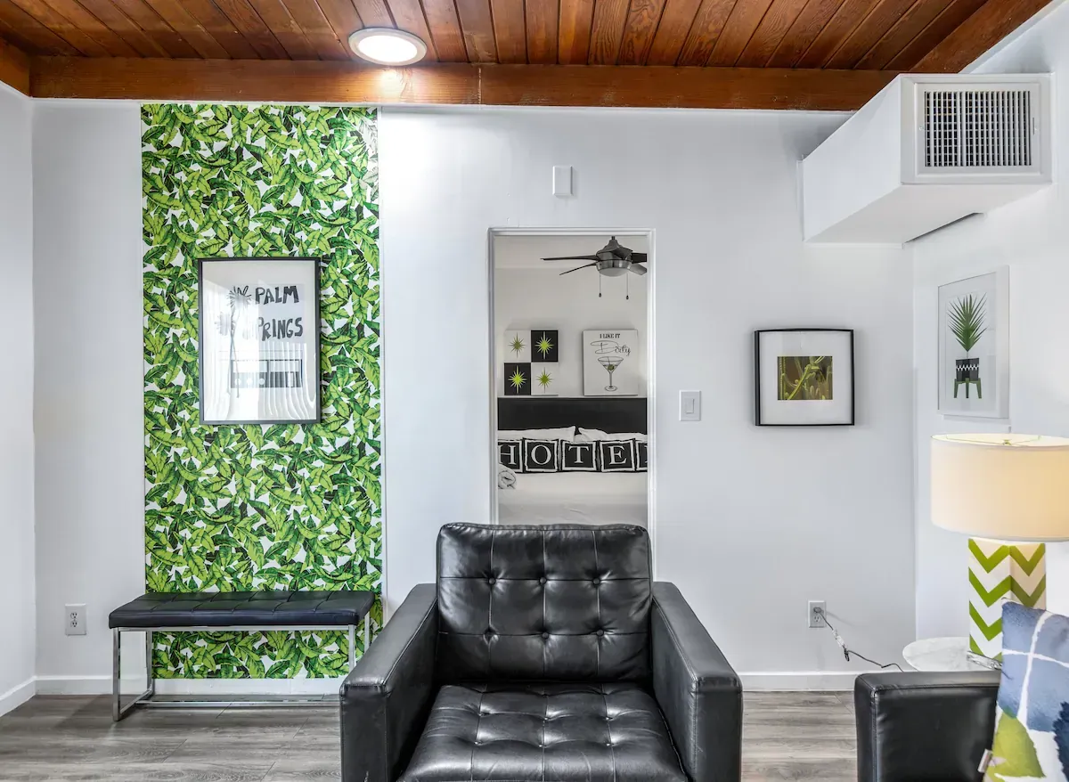 Modern waiting room with black leather chairs, green accent wall, and wood-paneled ceiling