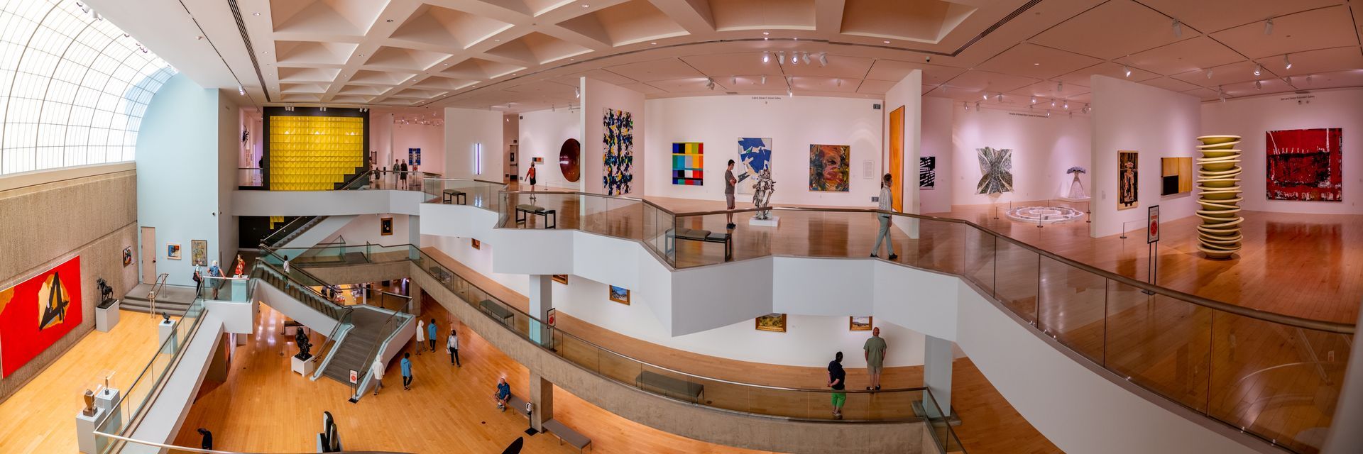 Person in a red dress stands facing a landscape painting in a minimalist gallery.