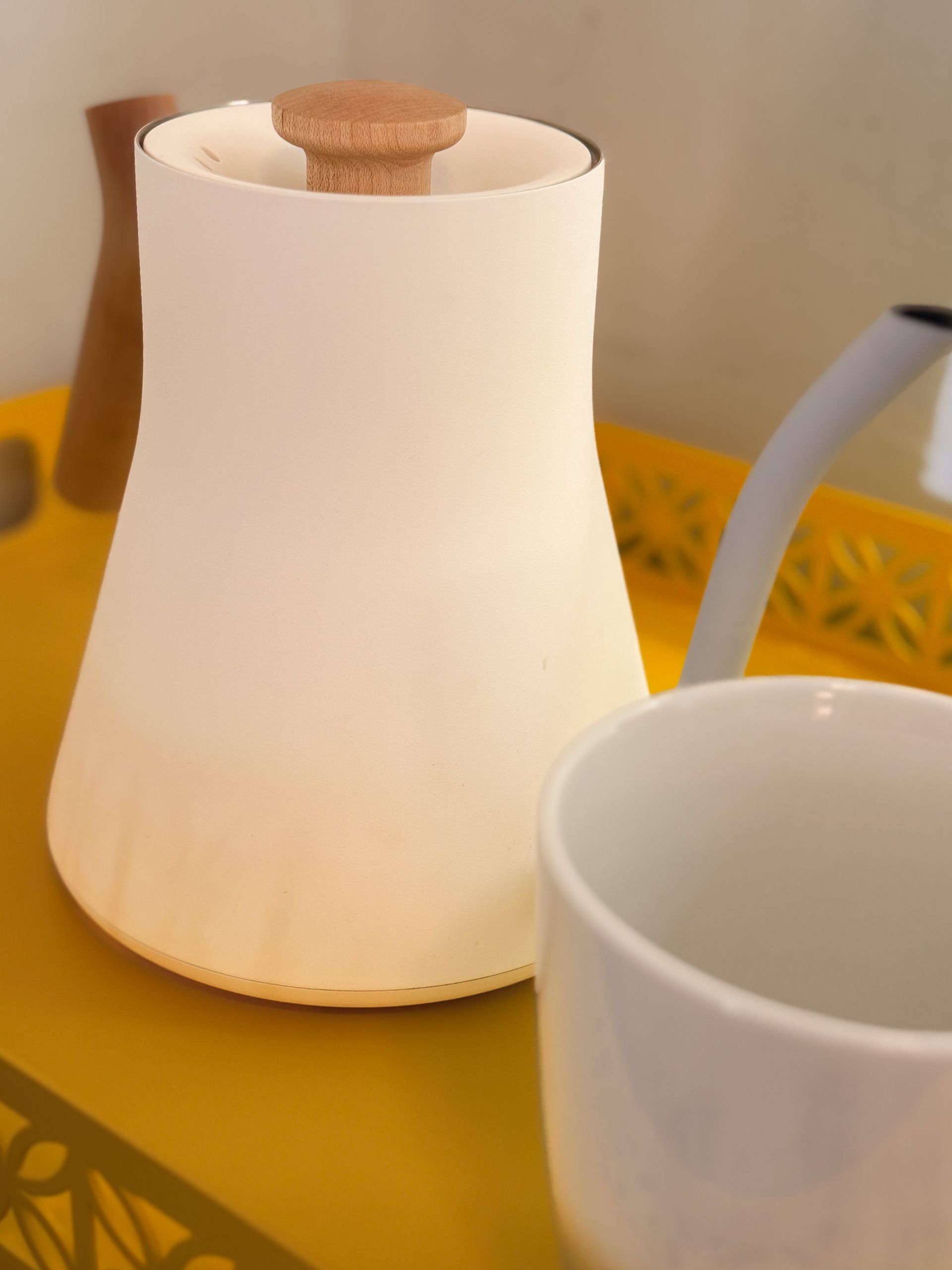White ceramic diffuser on yellow table beside a white cup