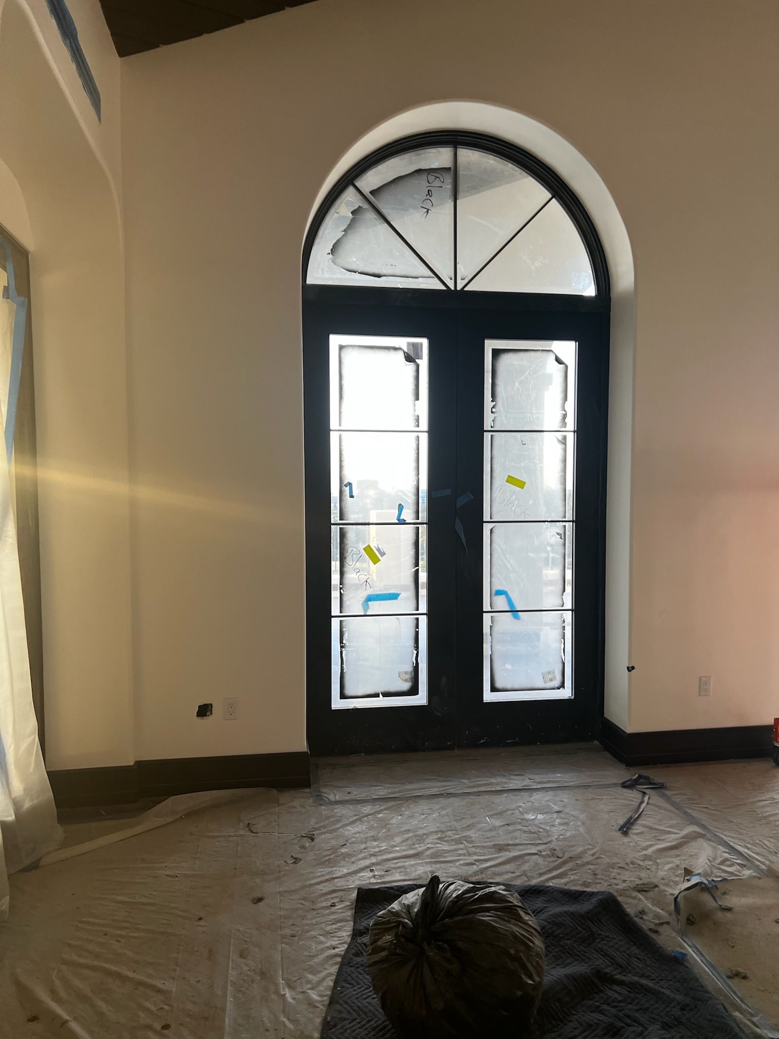 Black arched door with glass panes, white walls, and a pumpkin.