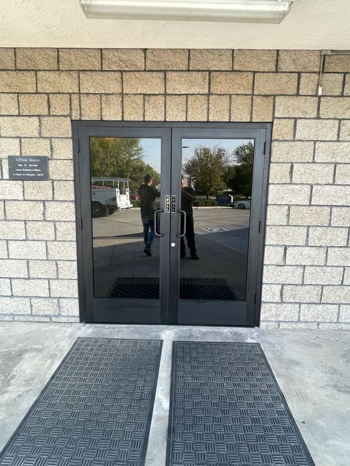 Man in a blue jacket opening a black glass door in an office; Gold Star sign visible.