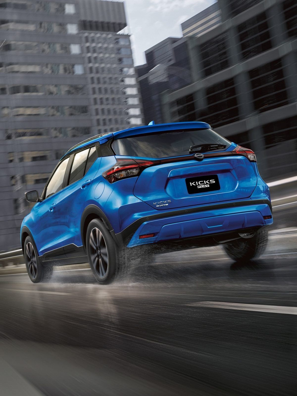 Un SUV azul circula por una calle mojada de la ciudad con edificios borrosos al fondo.