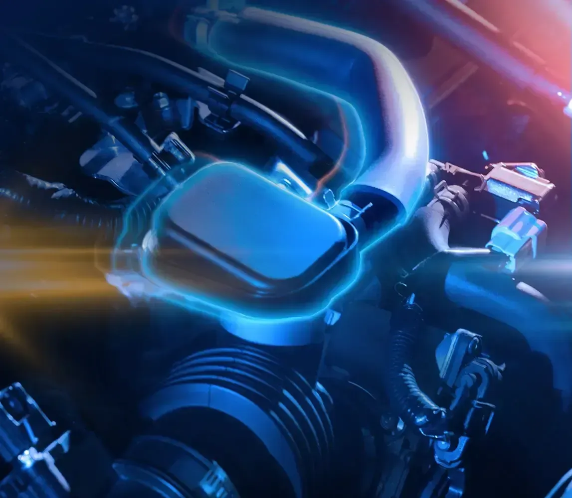 Primer plano de un motor de coche iluminado en azul con tuberías cromadas y reflejos brillantes.