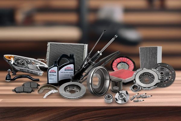 Varias piezas y herramientas de automóviles dispuestas sobre una mesa de madera en un entorno de taller.